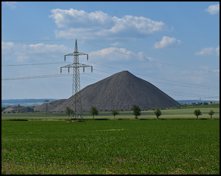 Eine Spitzkegelhalde hinter einer Stromleitung