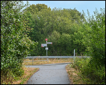 Ein Radweg endet an einer Kreuzung mit einem Wegweiser in verschiedene Richtungen