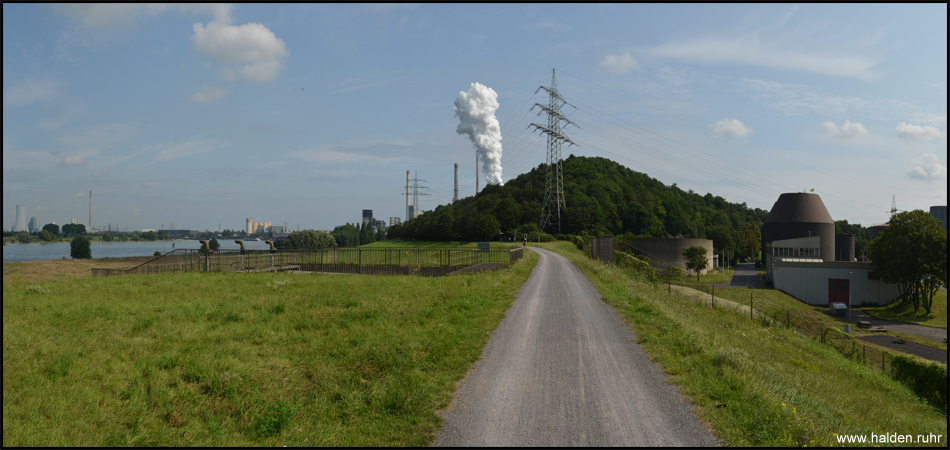 Ein Vulkan? Hinter dem Alsumer Berg am Rheinufer versteckt sich die Kokerei Schwelgern, die gerade Koks löscht Blick vom Radweg auf dem Rheindeich in nördlicher Richtung. Rechts liegt die Kläranlage Alte Emscher