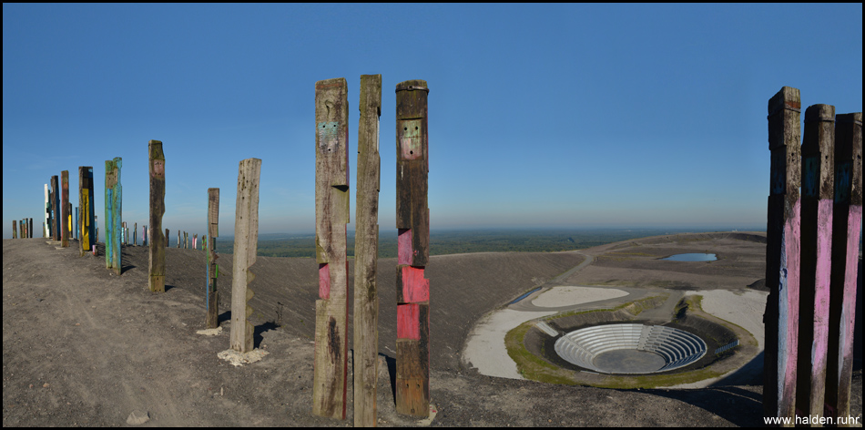 Blick von den Totems auf das tief im Kessel unterhalb gelegene Bergtheater auf dem Gipfel der Halde Haniel (90°-Panoramabild)