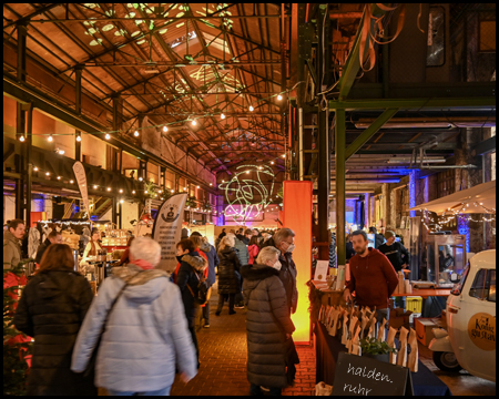 Bunt beleuchtete Industriehalle mit einem Weihnachtsmarkt