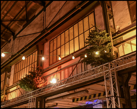 Fabrikhalle mit Weihnachtsbäumen und Lichterketten