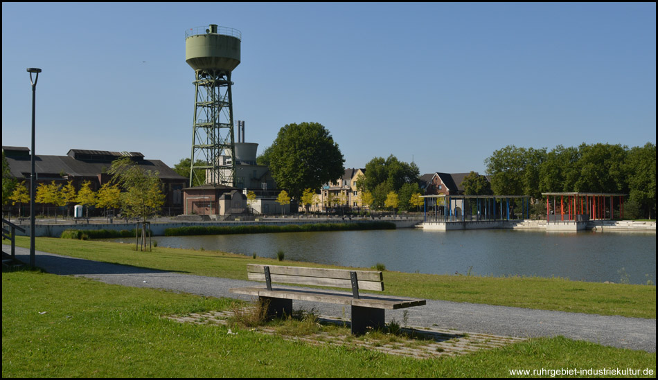 Bank am Seeufer mit guter Sicht auf den See mit den typischen überdachten Stegen und dem Wasserturm