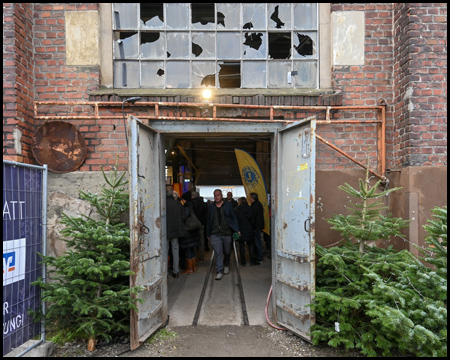 Eingang zu einer maroden Halle mit zerbrochenen Fenstern und rostigen Türen