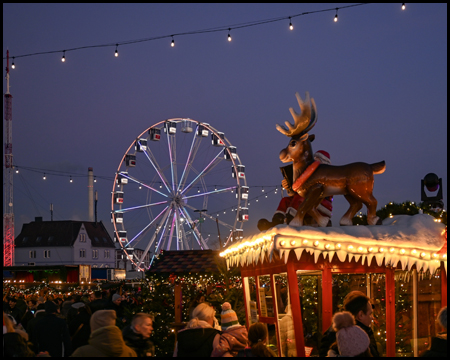 Rentier-Figur auf einer Kasse von einem Kirmes-Fahrgeschäft. Im Hintergrund Riesenrad