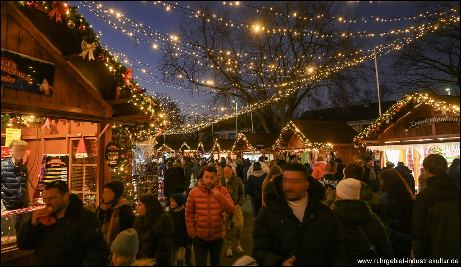 Weihnachtsmarkt-Buden mit LED-Beleuchtung an Lichterketten über dem Weg dazwischen