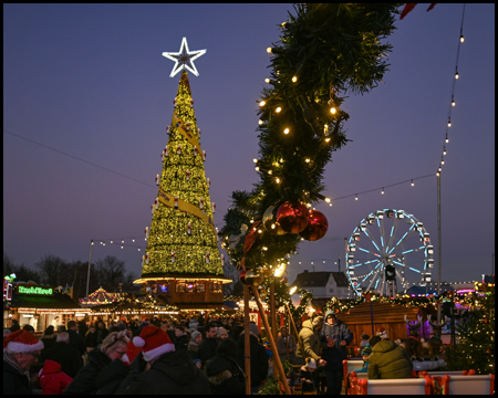Weihnachtsbaum und Riesenrad, im Vordergrund eine Weihnachtsdekoration mit Kugeln und Lichterkette