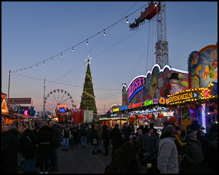 Weihnachtsmarkt mit Riesenrad und Weihnachtsbaum in der dunkelheit