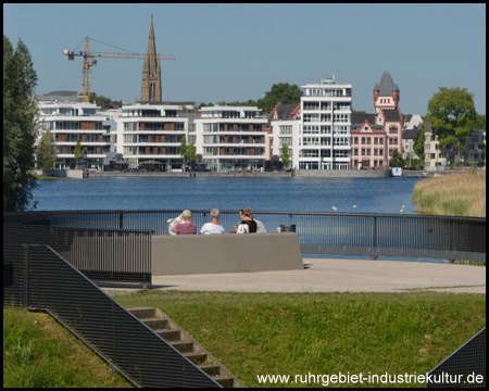 Man liest Zeitung und blickt über den See nach Hörde