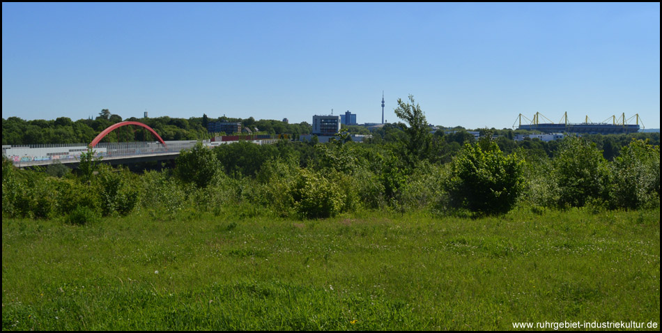 Blick von einer Wiese oberhalb des Radweges auf die Schnettkerbrücke der A40 bzw. B1, den Florian und das Stadion