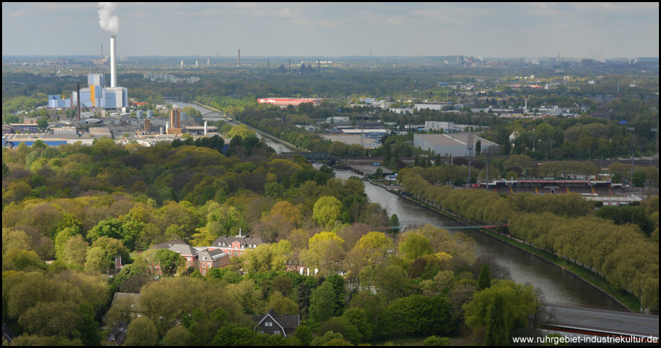 Die Sonne scheint durch dichte Wolken und beleuchtet das rosafarbene Schloss Oberhausen im Kaisergarten nebenan.  Gut zu erkennen ist auch die Slinky-Brücke über den Kanal, allerdings im Wolkenschatten... 