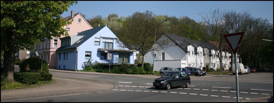 Kreuzung Plutostraße / Dürerstraße mit der Halde, die sich hinter den Häusern erhebt