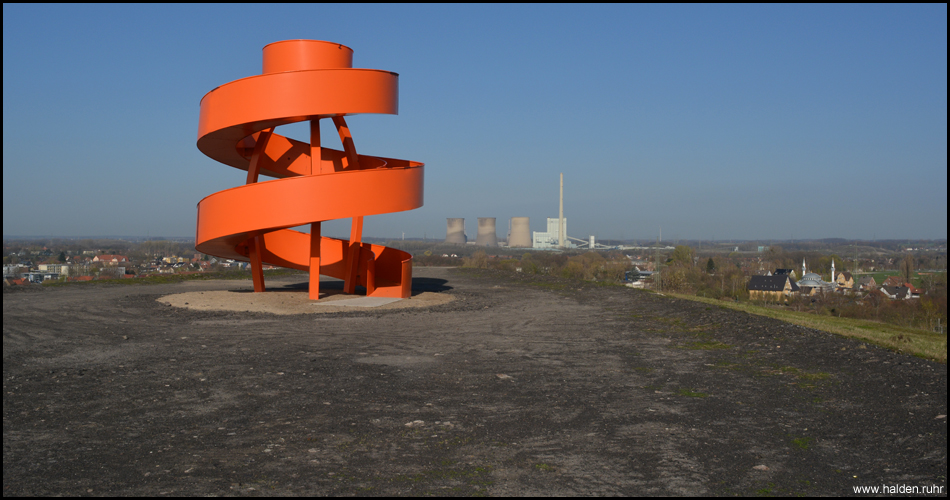 Leuchtend orange präsentiert sich das Haldenzeichen auf dem Gipfel. Allgegenwärtig ist das Kraftwerk in Werne-Stockum