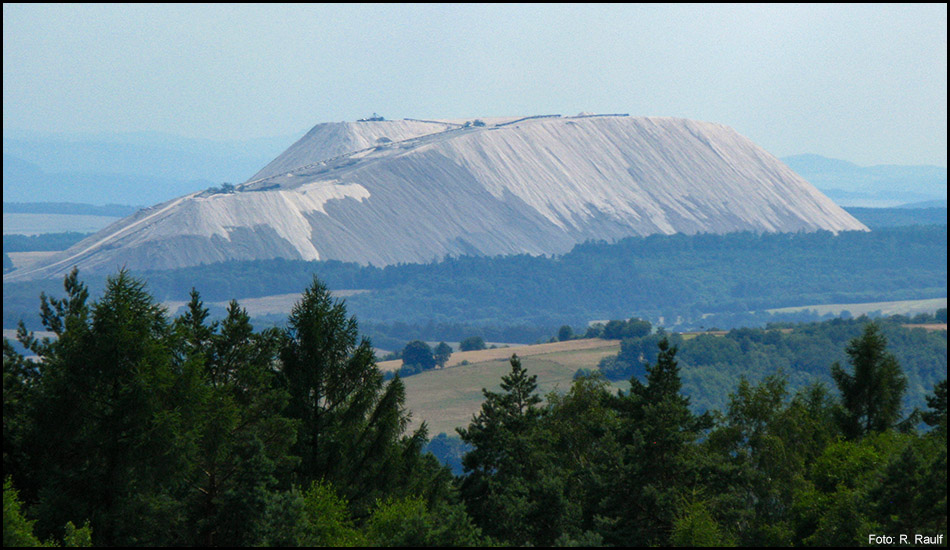 Aus der Ferne sichtbarer Kaliberg in einer Ebene. Im Vordergrund Baumspitzen, Wälder und Felder.