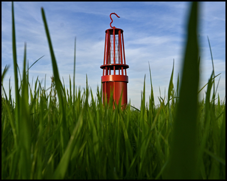 Froschperspektive einer Wiese mit der roten Grubenlampe der Halde Rheinpreußen