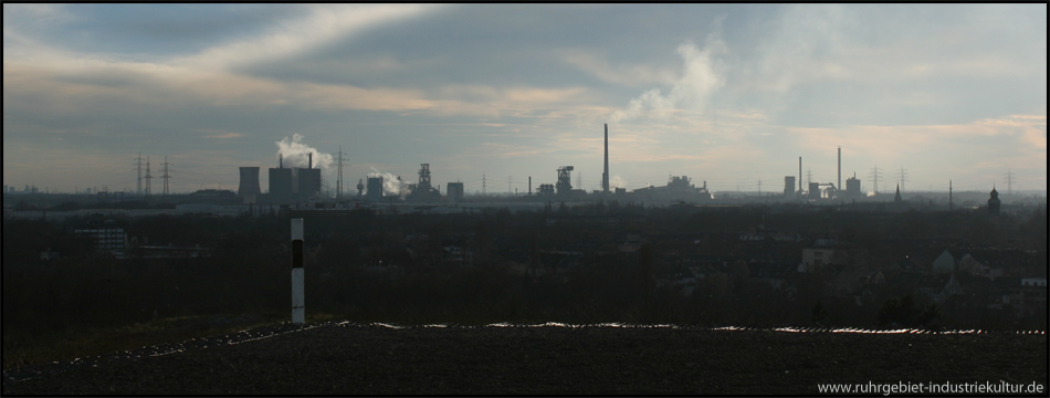 Blick vom Hochplateau nach Süden auf eine imposante Industriekulisse am Horizont