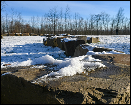 Große Steine mit Schneeresten auf einer weiß verschneiten Wiese