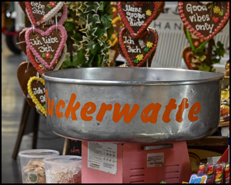 Eine Wanne für Zuckerwatte, dahinter Lebkuchenherzen mit Beschriftung