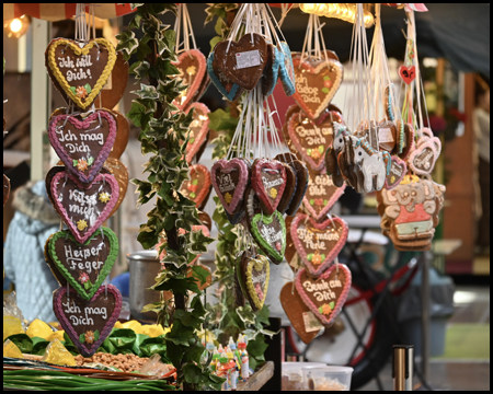 Jahrmarkt-Stand mit Lebkuchenherzen, auf denen Komplimente stehen: "Ich mag dich" oder "ich will dich"