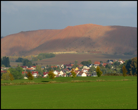 Rote Halde hinter einem Dorf