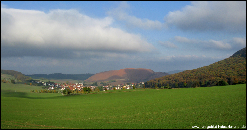 Bild von einem Tal, im Hintergrund eine große rote Abraumhalde