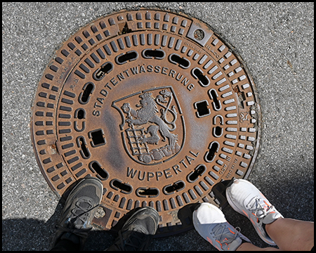 Ein Symbolbild mit einem Kanaldeckel und dem Wappen von Wuppertal
