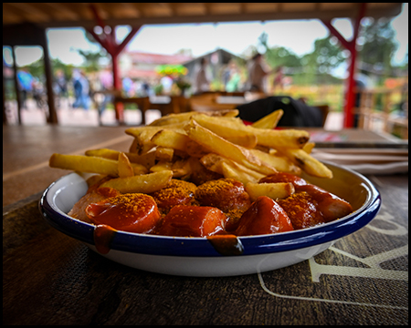 Ein Teller mit Currywurst und Pommes auf einem Tisch