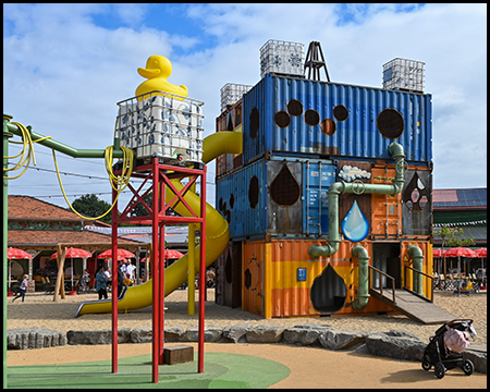 Spielplatz mit Fracht-Containern und einem Wassertank mit gelber Quietsche-Ente