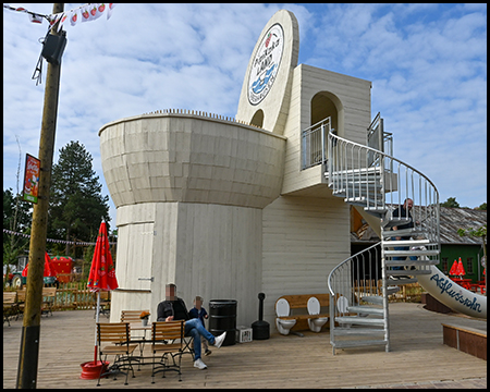 Ein Gebäude in Form einer großen Toilette mit Wendeltreppe in den ersten Stock, wo sich in Höhe der Sitzfläche eine Aussichtsplattform befindet