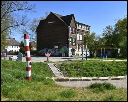 Haus hinter einem Graben mit Holzskulptur