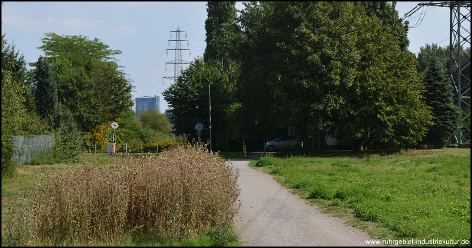 Radweg an den ersten Metern des offenen Flüsschens Kleine Emscher, im Blick zurück ist der Gasometer Oberhausen zu sehen