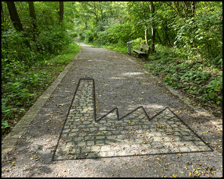 Ein Mosaik mit Fabrik-Symbol auf einem Waldweg