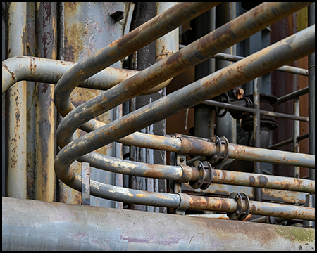 Detailfoto einer Industrieanlage: Parallel verlaufende Rohre, die eine gleichmäßige Biegung machen