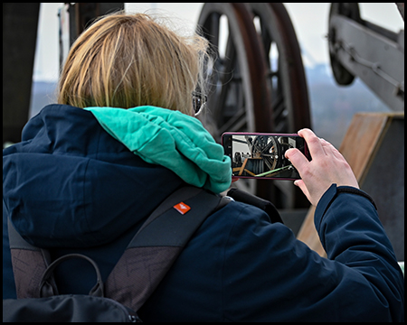 Eine Frau fotografiert mit einem Smartphone Teile einer Industrieanlage
