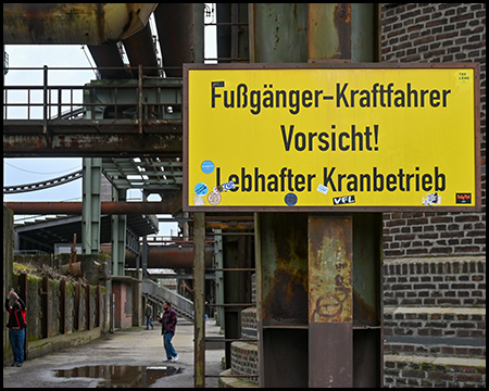 Industriegelände mit einem großen Schild, das vor Kranbetrieb warnt