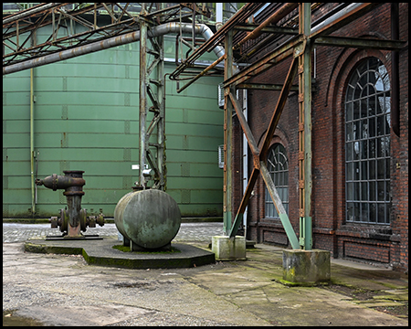 Industrieanlage mit Gasometer, Backsteinhalle und einem Gastank