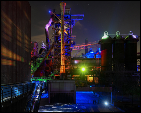 Aussicht von höherer Position auf einen illuminierten Hochofen im Landschaftspark Duisburg-Nord