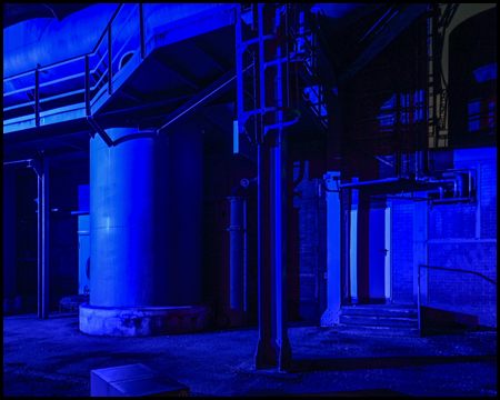 Blau beleuchtete Industrieanlagen mit einem Silo
