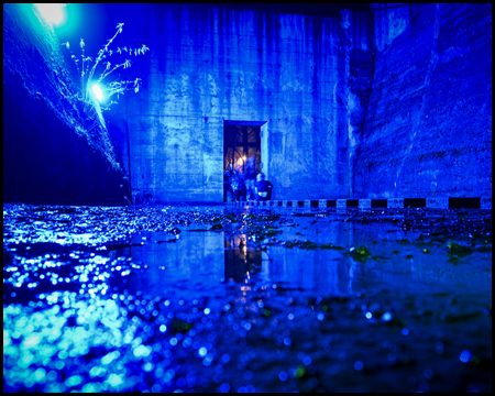Froschperspektive eines blau beleuchteten Bunker-Raumes mit Wasser auf dem Boden