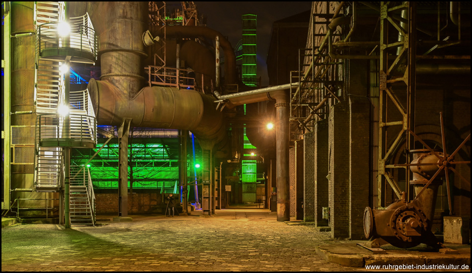 Industrieanlagen in der Nacht mit Straßenbeleuchtung und etwas grüner Beleuchtung