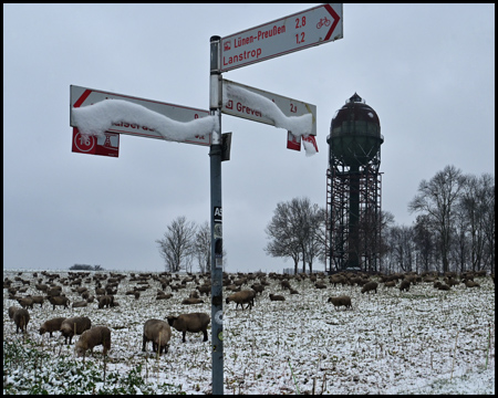 Verschneiter Rad-Wegweiser und Wasserturm im Schnee