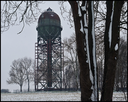 Wasserturm und Baumstamm nebeneinander im Schnee