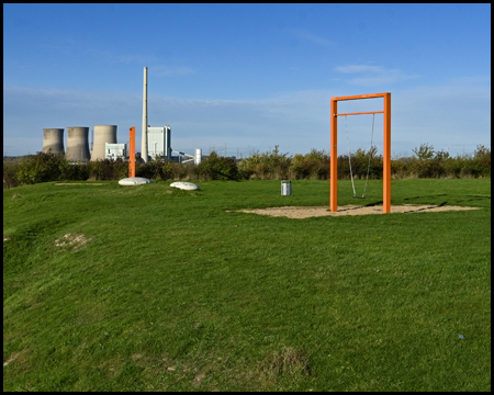 Schaukeln im hügeligen Lippepark mit Kraftwerk im Hintergrund