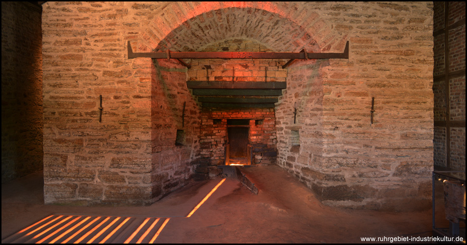 Hochofen von 1834 mit Rotglühendem hinter der Ofentür, Licht-Installation simuliert den Weg des Roheisens durch die Kanäle