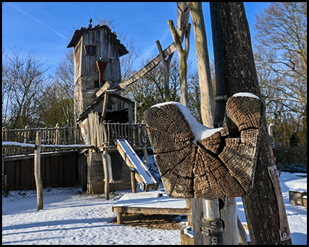 Holzspielturm mit Rutsche im Schnee
