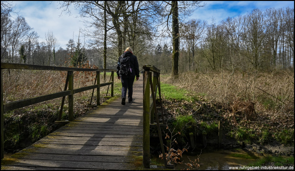 Eine Frau überquert mit einer Brücke einen Bach