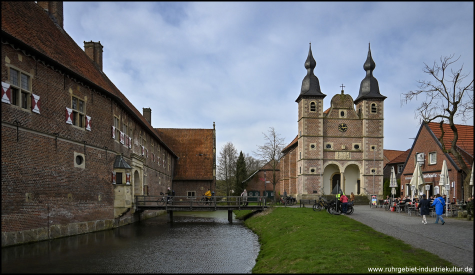 Vorburg mit Gräfte, die mit einer Brücke überwunden wird. Daneben eine kleine Kirche mit zwei Türmen mit filigranen Turmhauben. Sie steht schon neben den Häusern der historischen Burgfreiheit.