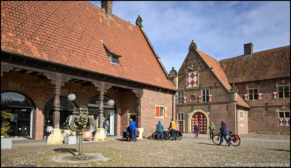 Szene mit Radfahrern auf dem Schlossplatz von Raesfeld mit der Vorburg im Hintergrund