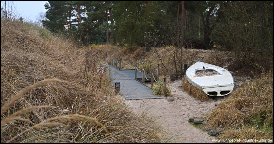 Inmitten der Dünenlandschaft ist ein Boot gestrandet