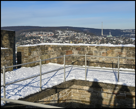 Eckiger Turm der Ruine Volmarstein mit Schnee und angedeuteter Siedlung weiter unten im Tal